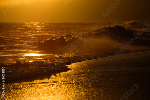 Gold sky and ocean water. Waves splashes. Sunset over sea with golden dramatic sky panorama. Calm sea with sunset sky. Ocean and sky background.