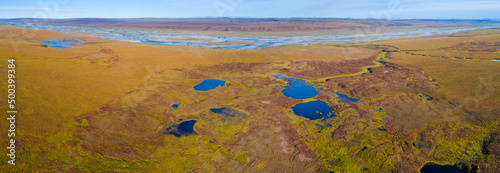 Aerial view of tundra wetland of the North slope in Alaska with river and lakes in autumn colors 