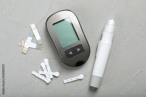 Glucometer, lancet pen and strips on grey table, flat lay. Diabetes testing kit