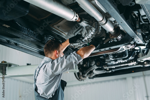 Portrait of a mechanic repairing a lifted car.