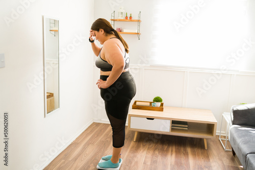 Stressed overweight woman using the weighing scale