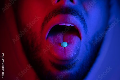 Close up of man mouth swallowing ecstasy drugs. Man taking MDMA ecstasy pill.