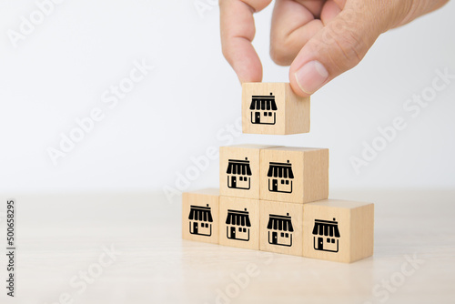 Franchise, Close-up hand choose cube wooden toy block stack with franchises business store icon for franchising business marketing plan to growth and branch expansion and banking loan.