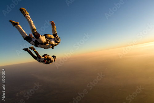 Skydiving couple in freefall at sunset, togetherness concept