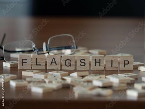 flagship word or concept represented by wooden letter tiles on a wooden table with glasses and a book