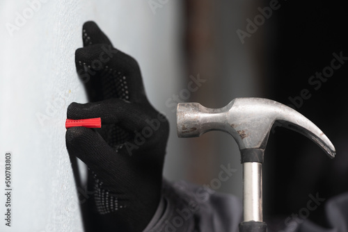 Worker inserts a plastic dowel into the wall close up.