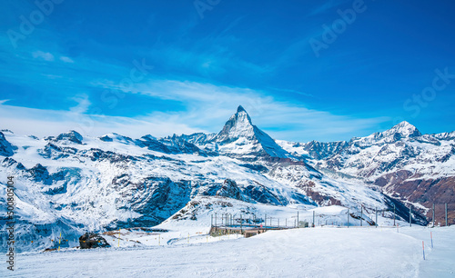 Scenic view of snowcapped matterhorn mountain peak. Beautiful snow covered white landscape against sky. Alpine region during winter.