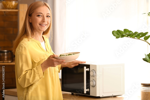 Mature woman heating food in microwave oven