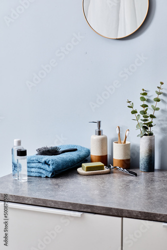 Toilet table with hygiene products and morning accessories in bathroom with mirror on wall