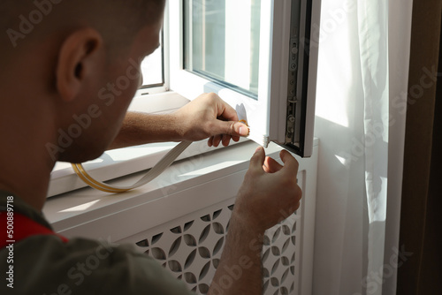 Man putting rubber draught strip onto window, closeup