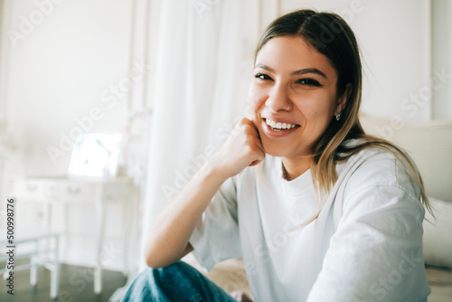 Portrait of happy attractive caucasian woman sitting in a bedroom and looking on camera.