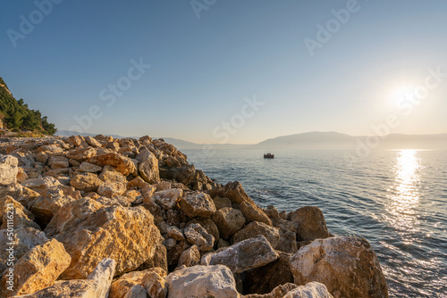 Sunset at rocky stone beach in Albania. Adriatic sea, peninsula Karaburun on horizon