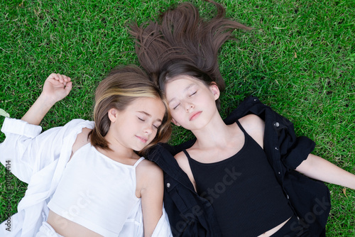 fraternal twins sisters. blonde and brunette teen girls in fashionable black and white clothes outdoors. sisterhood, siblings spending time together.