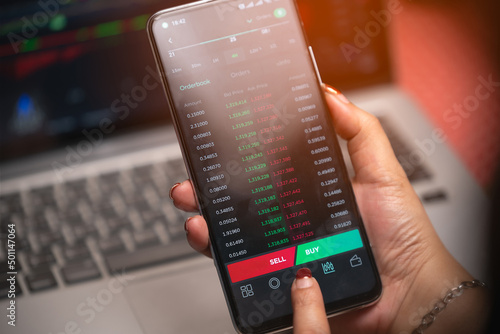 Women's hands are looking at data and making arbitrage trading on cryptocurrencies market on smart phones.