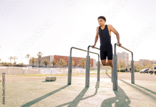 Dips exercise. Young guy doing calisthenics exercises. Outdoor training and working out. 