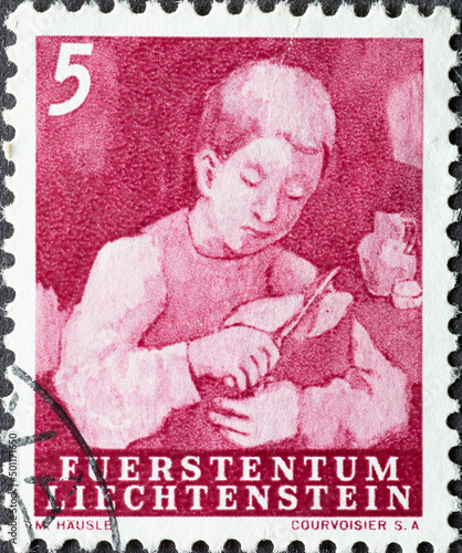 LICHTENSTEIN - CIRCA 1951: a postage stamp from LICHTENSTEIN , showing a Boy Cutting Bread . Circa 1951