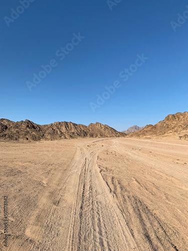 Car tire tracks leading to small canyon with red sandstone rocks, Nabq protected area, Sharm El Sheikh, Sinai peninsula, Egypt, North Africa. Egyptian safari