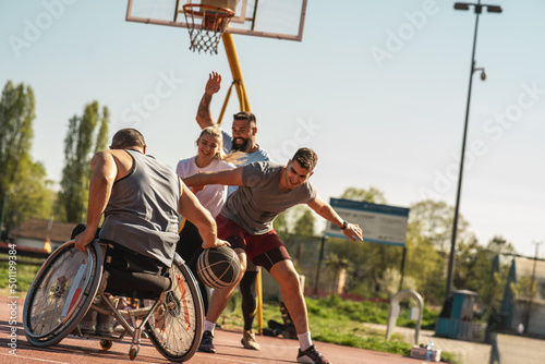 A physically challenged man in a wheelchair fearlessly engages in a spirited game of basketball with his supportive friends, breaking barriers and proving that passion and teamwork know no bounds. 
