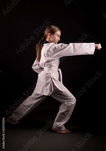 girl in kimono practicing taekwondo on black background. Sports banner. 