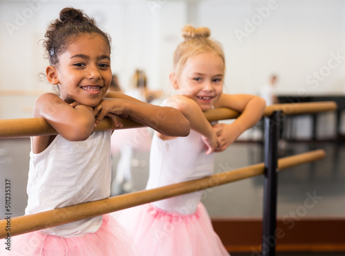 Two little girls practicing ballet elements and positions in dance studio