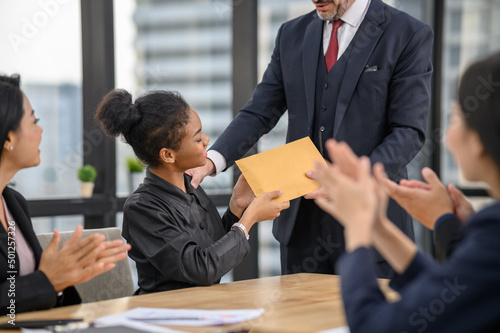 Happy young African woman employee excited by unexpected money bonus in envelope from boss, black person rewarded for high work results, praised for successful project completion. Achievement concept