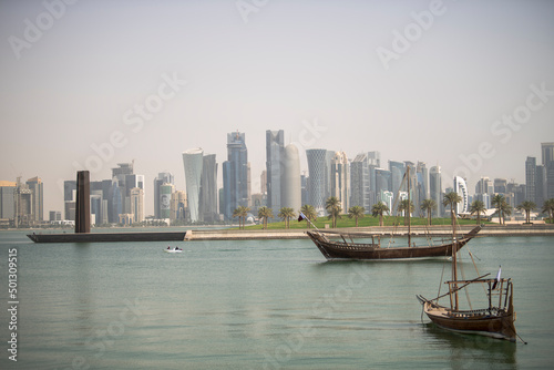 Doha,Qatar- April 24,2022 : Traditional dhow boats with the futuristic skyline of Doha in the background.