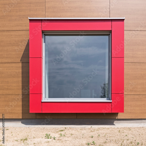 Czerwone kwadratowe okno na elewacji. Kadr frontalny
