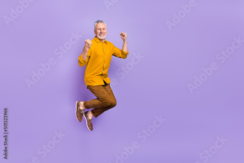 Full length photo of mature man jump fists hands rejoice victory triumph isolated over purple color background