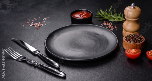 Empty round black plate on dark moody black background with copy space