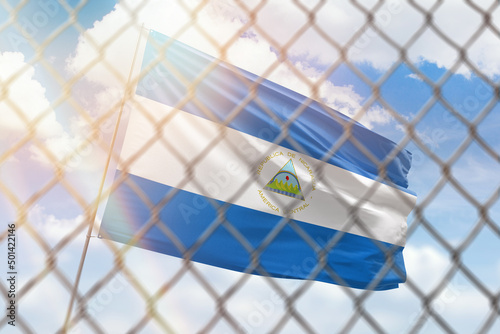 A steel mesh against the background of a blue sky and a flagpole with the flag of nicaragua