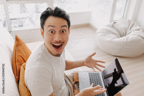 Surprised and wow face of Asian man happy with the result in his tablet.
