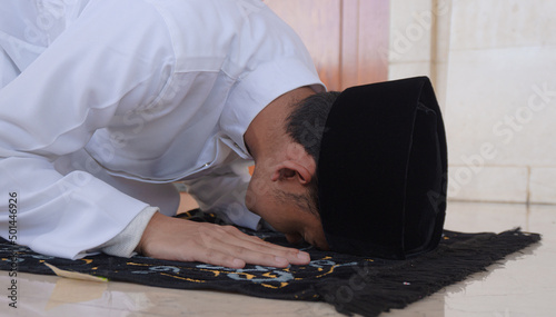 Portrait of a Muslim man praying in an act of prostration called Sajdah or prostration. Side view of a Muslim man praying with a prostration pose on the ground in a mosque