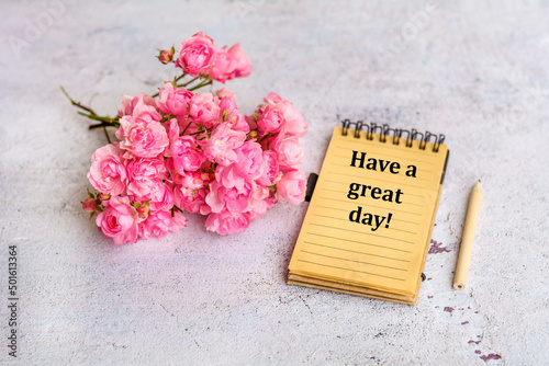Notebook with have a great day message and bouquet of roses flowers 