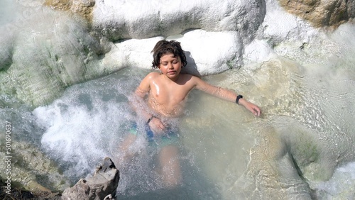 Boy 7child 7 years old relax in Bagni San Filippo natural bath in tuscany, Italy. sulphurous water and therapy for respiratory problems in children thermal baths, Siena ,Tuscany