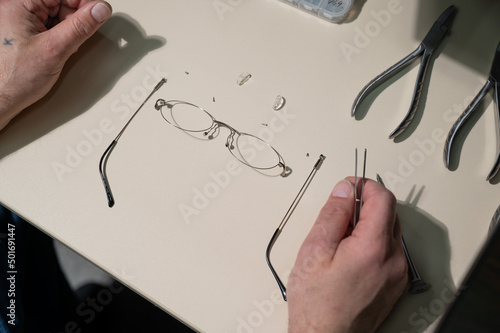 A man repairs a broken eyeglass frame. Close-up of the ophthalmologist's hands