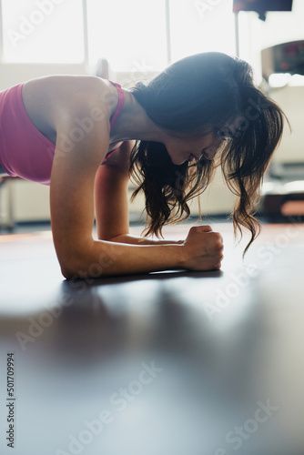 Close up of a fit sportswoman doing planks endurance in a gym.