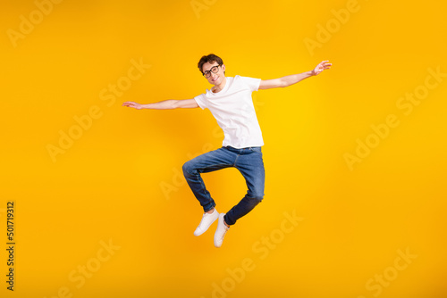 Full body photo of young cheerful man good mood arms wings fly air jumper isolated over yellow color background