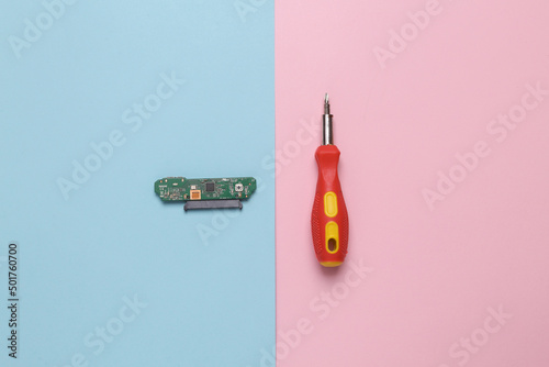 Microchip with screwdriver on blue pink pastel background. Flat lay