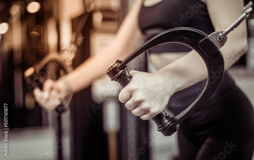 Young fit woman trains pectoral misci in a crossover exercise machine. Girl works out in modern gym