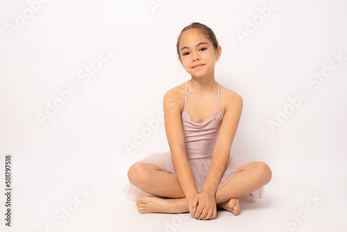 Beautiful little ballerina sitting isolated over white background.