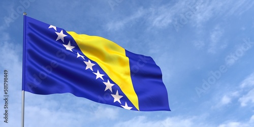 Flag of Bosnia and Herzegovina on flagpole on blue sky background. Bosnian flag fluttering in the wind against a sky with clouds. Place for text. 3d illustration.