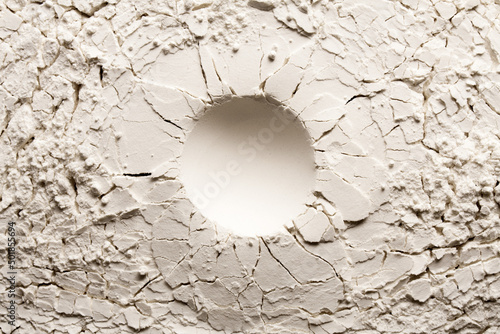 Round crater on white backgroung with crack. Cracked background with a round hole.