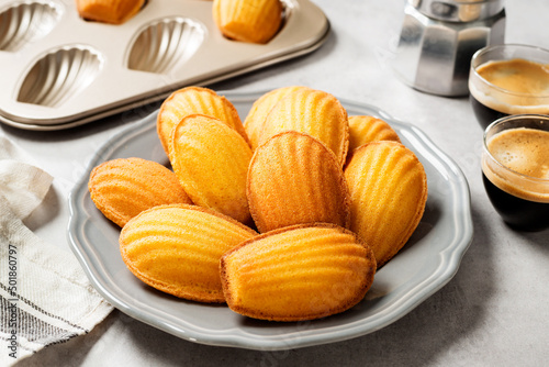 Perfect French madeleine cookies, buttery and delicate, served with cup of coffee. Light gray background.