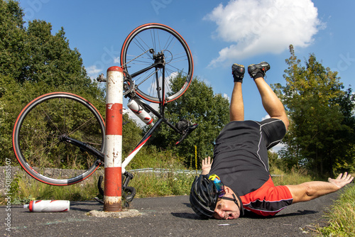 The unhappy cyclist falls of the bike beside the barrier on a bicycle path.