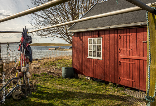 a red fisherman´s hut with fishing equipment on a danish shore
