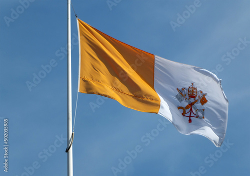 vatican state flag flying against a bright blue sunlit sky