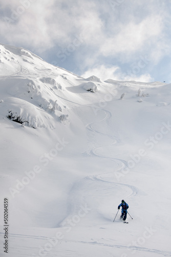 Athletic snowboarder ride down the untouched powder snow. Picturesque snow covered mountain scenery surrounds