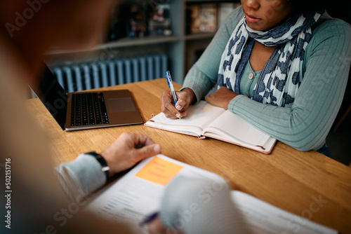 Close up of adult students learning in library.