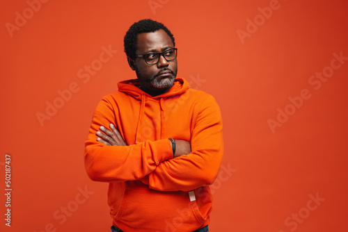 Black sad man in eyeglasses posing with arms crossed