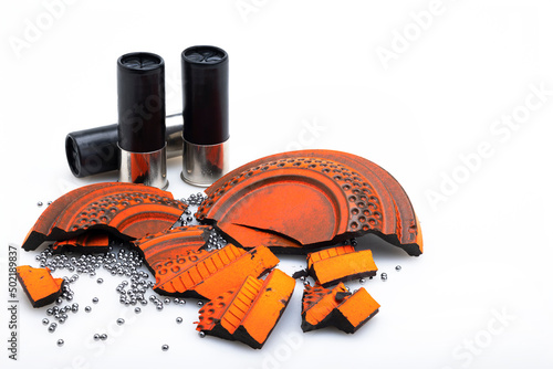 Broken pieces of flying clay pigeon target and shotgun shell bullets on white background , Gun shooting game